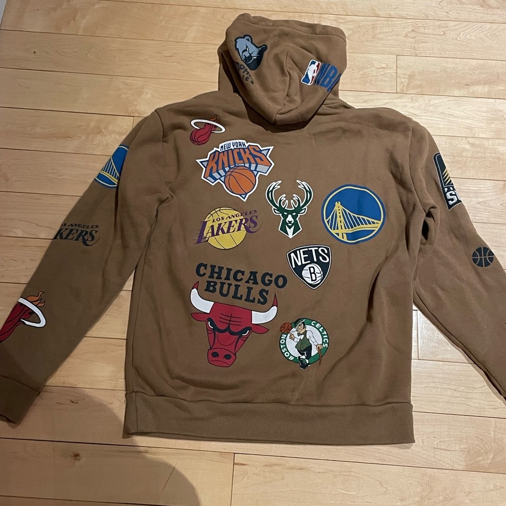 Men’s Hollister sweat shirt with hood,  tan with sports logos, size Small.